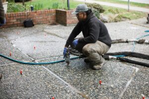 Installer injecting polylevel into the concrete in front of apartment building concrete services