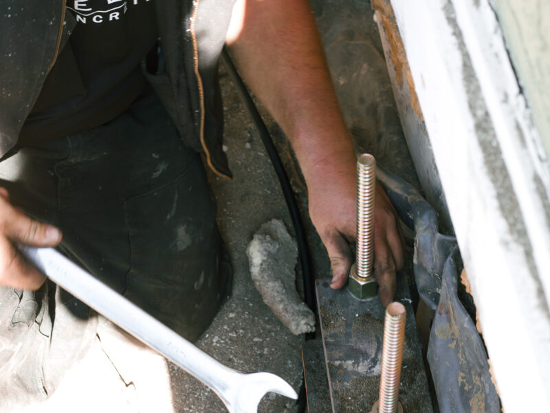 installer adjusting bracket on house foundation